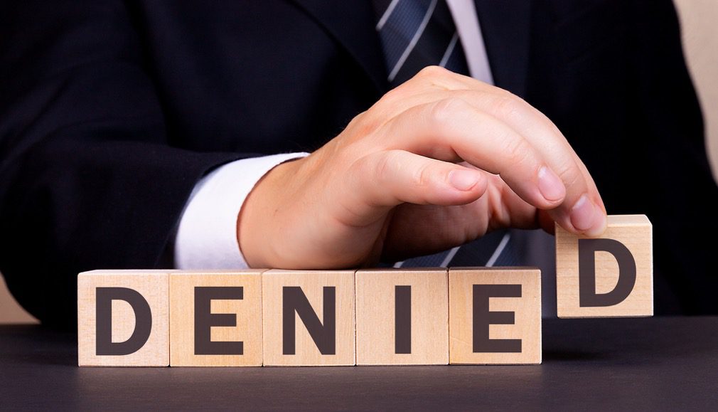 Man holding wooden block letters that say "denied," License Restoration in Michigan