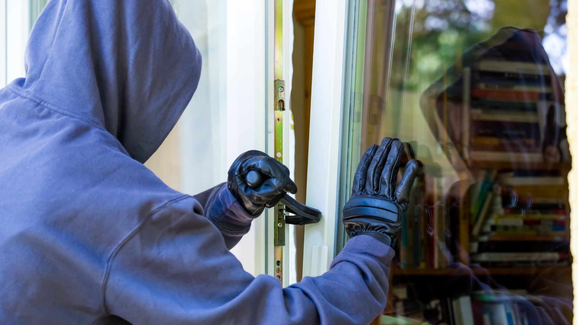 man with crowbar breaking and entering into a business