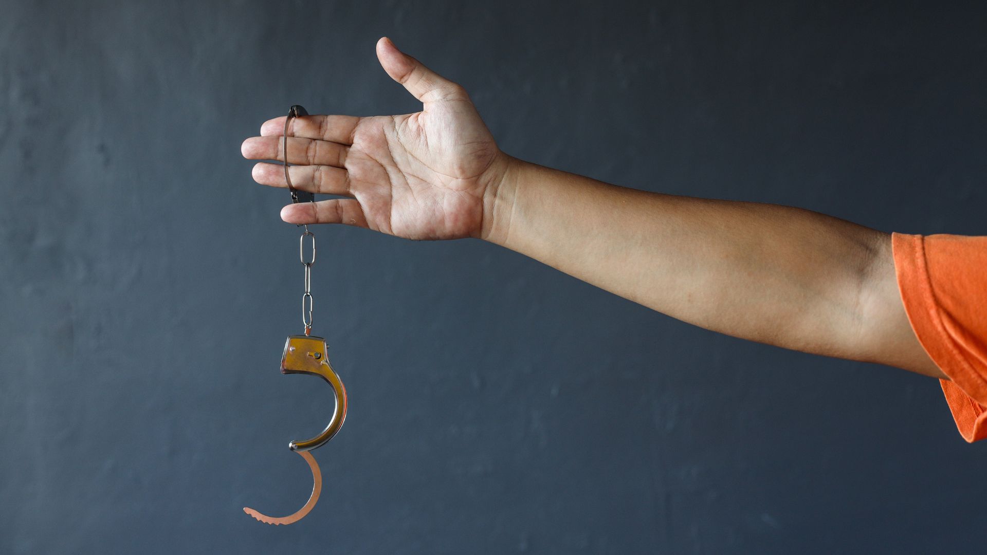 man holding hand cuffs and getting out of jail