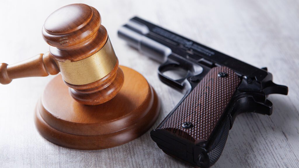 gun laying on table with judge's gavel