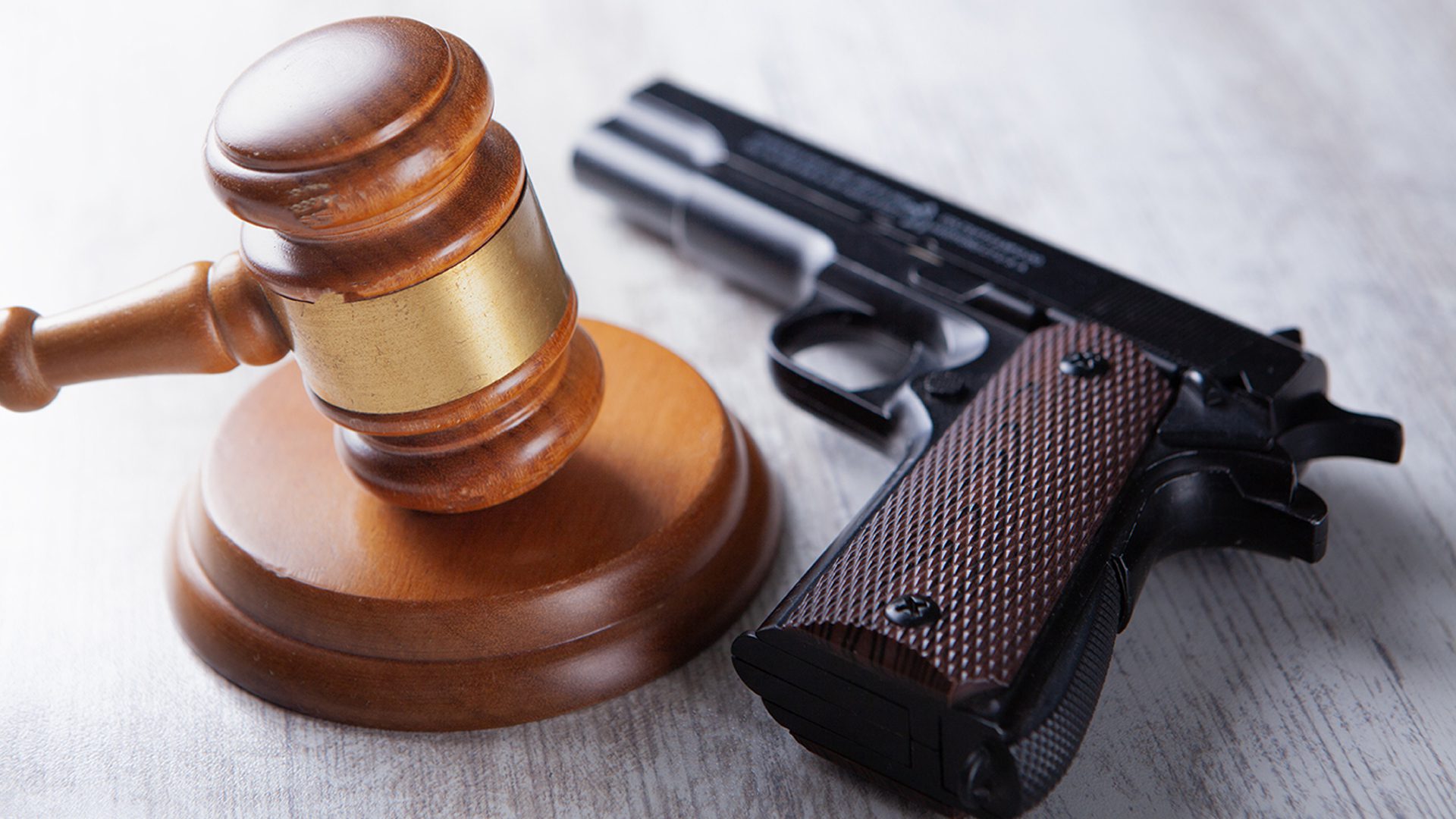 gun laying on table with judge's gavel