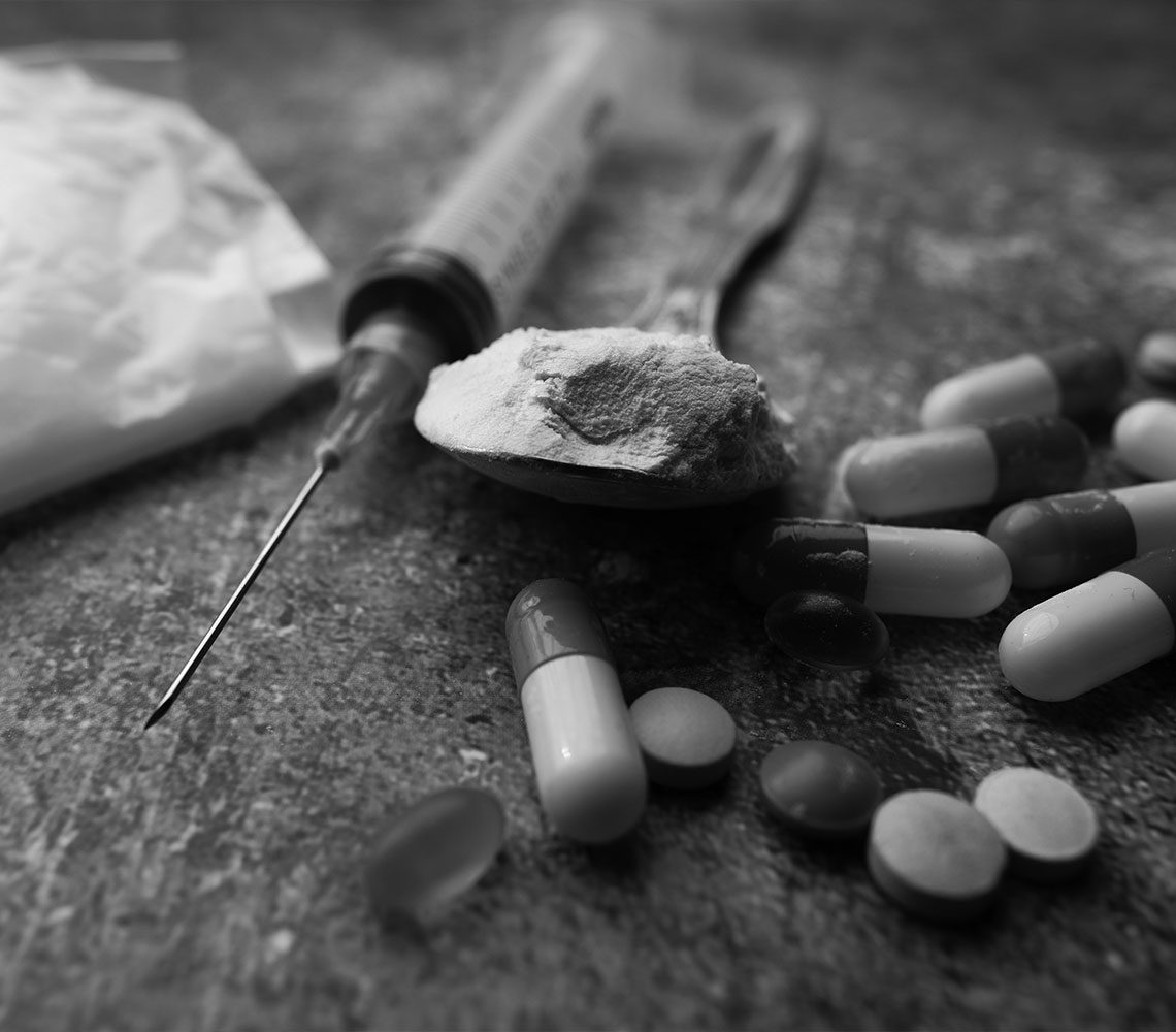 variety of pills and drugs close up of syringe and other drugs and pills found after arrest for drug possession charges