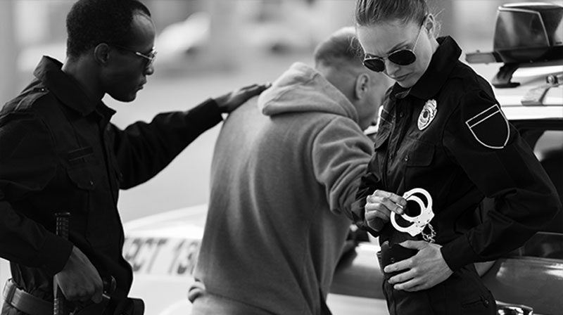 two cops arresting man two policemen arresting man for assault and placing him cop car