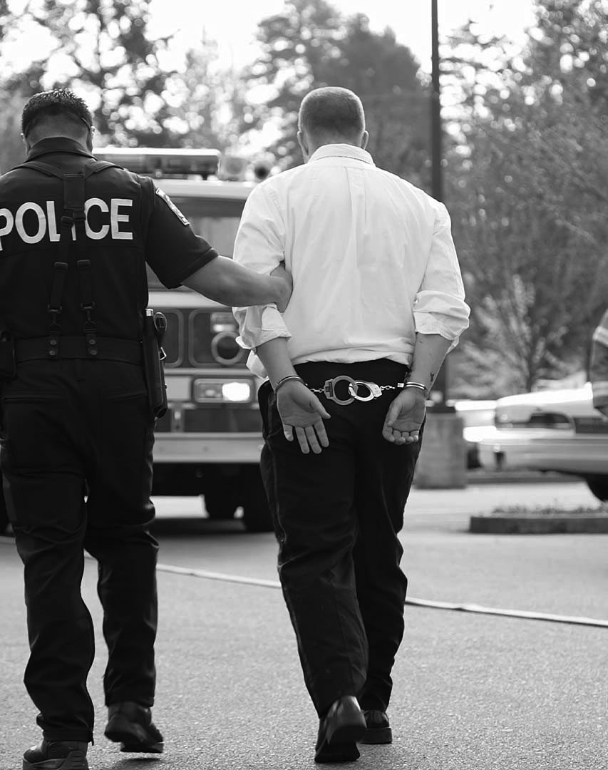 man arrested for assault man handcuffed being led to cop car by policeman arrested on assault charges