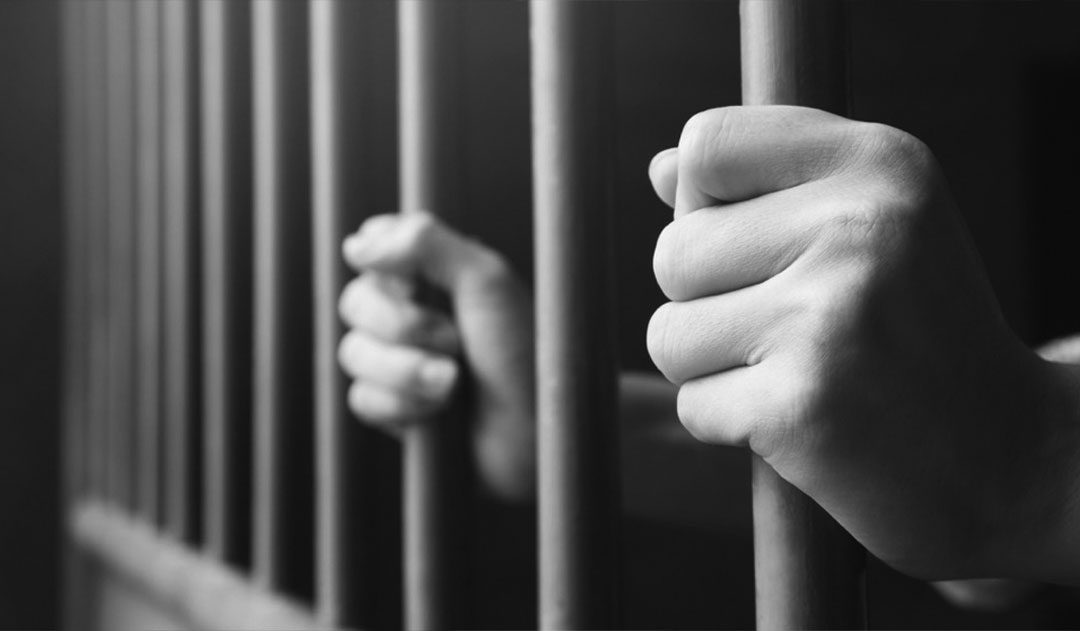 man holding jail cell bars close up of man clutching jail cell bars after being arrested for drug possession in michigan