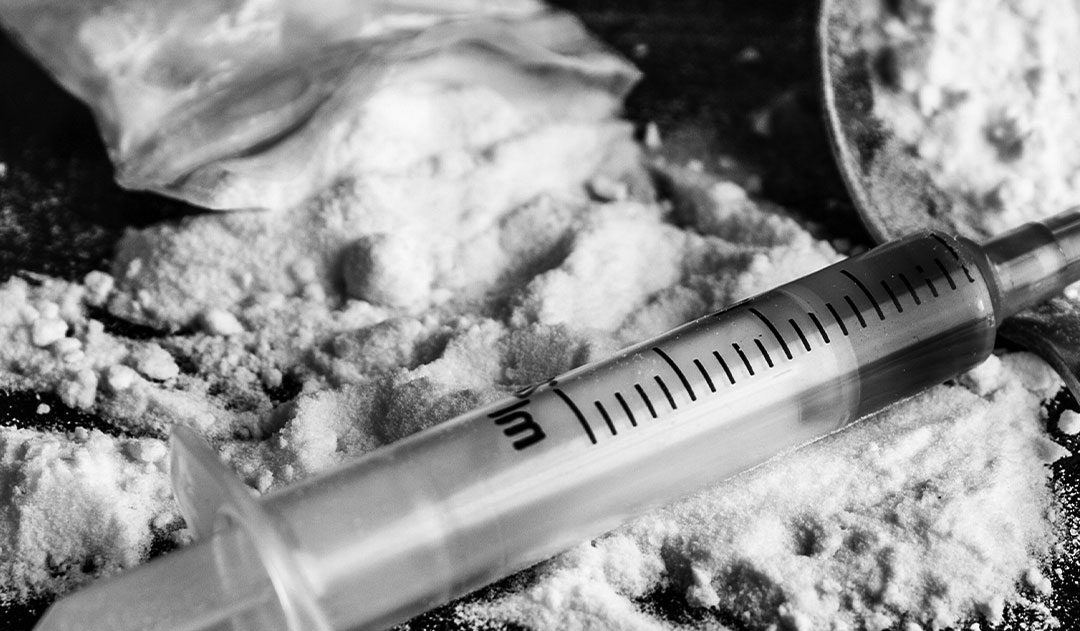 heroin and syringe close up of syringe and heroin powder on a table after drug possession charges in michigan