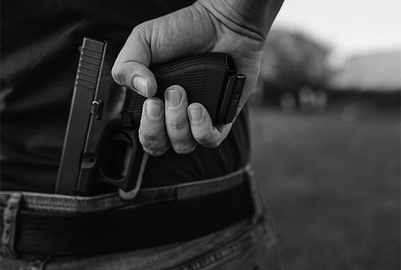 concealed handgun in pocket close up of man holding concealed carry handgun behind his back