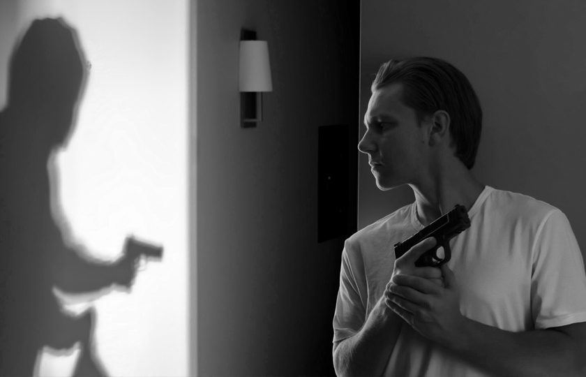 Man With Firearm For Self Defense man hiding in home with gun ready with shadow of man stalking him